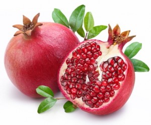 Juicy pomegranate and its half with leaves. Isolated on a white background.